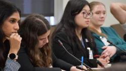 Washington Week participants sitting behind table with microphones listening intently.